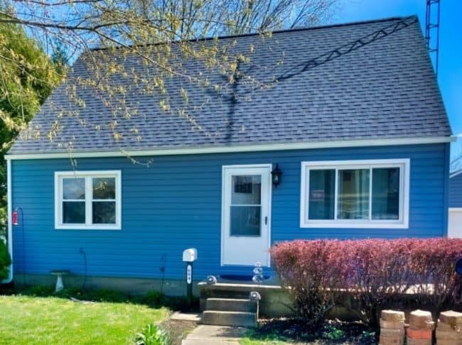 blue siding on home with newly installed grey shingled roof by local roofers