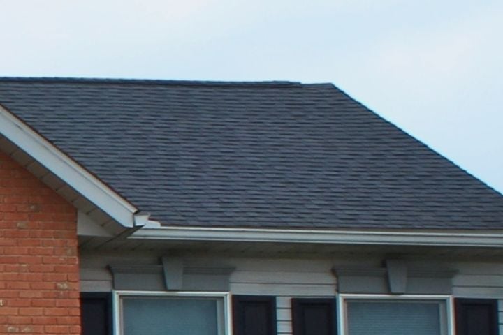 closeup view of roofers installed new shingles over upstairs bedroom windows