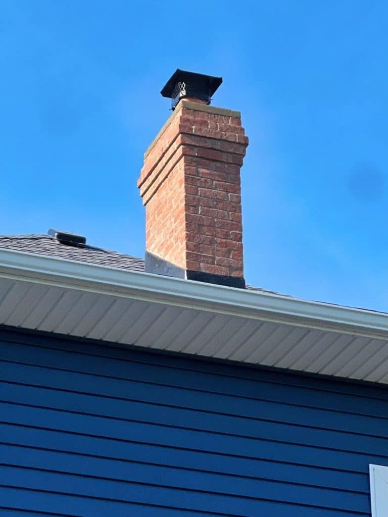 view of repaired chimney tuckpointing on a house with blue siding